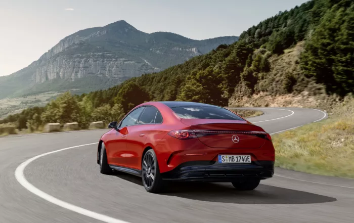 Mercedes-Benz CLA250+ EQ color rojo desde trasera 3/4 tomando una curva