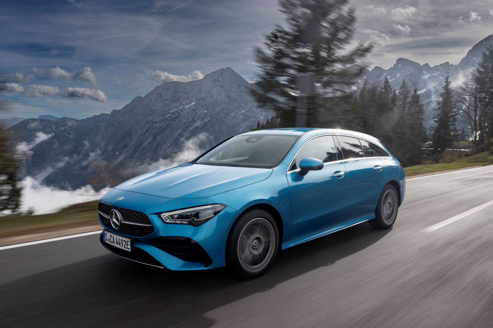 24C0347_114 Mercedes-Benz CLA 250e Shooting Break Híbrido color azul eléctrico. Vista 3/4 delantera circulado por una carretera con montañas al fondo.
